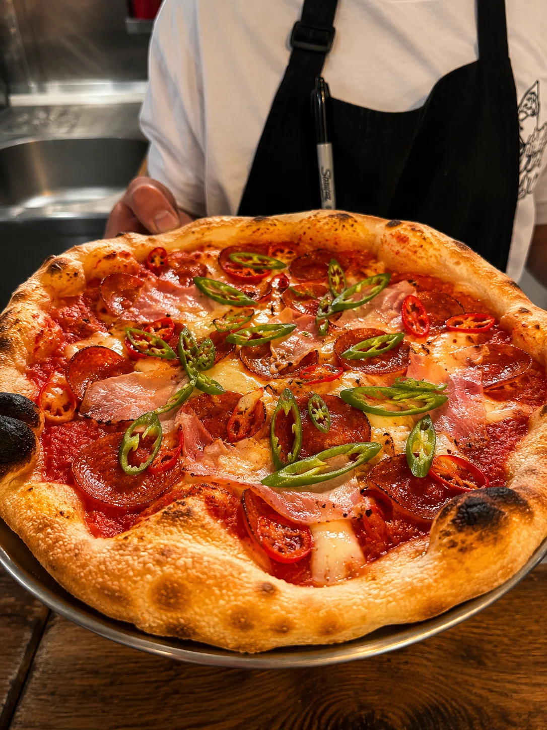 Lupa pizza topped with pepperoni, ham and sliced chillies
