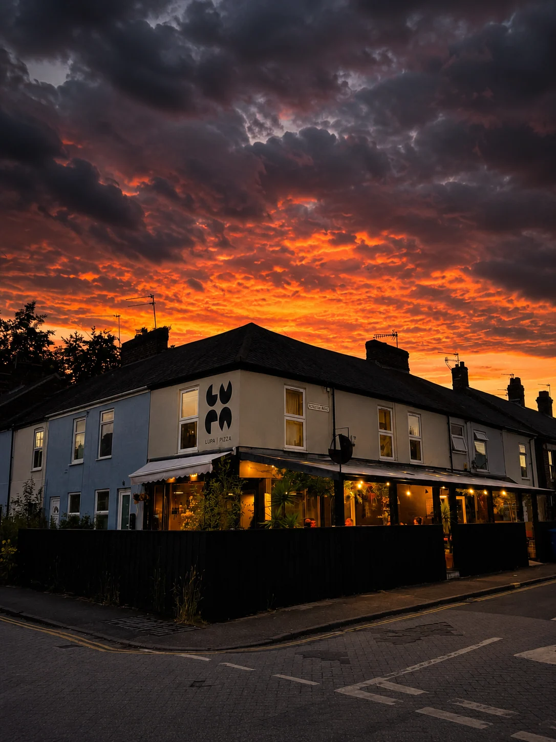 Lupa Pizza storefront beneath a vivid sunset